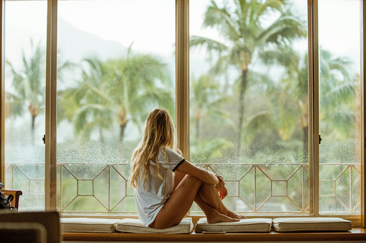 A girl at a window in Hawaii thinking about the view outside