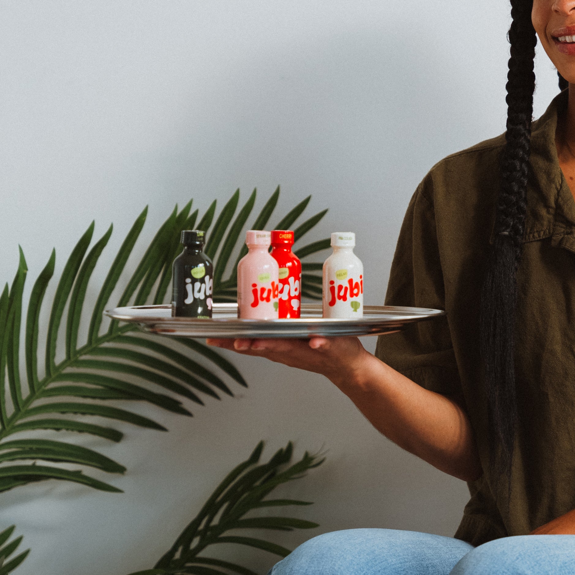 Person holding tray with Jubi Kratom bottles.