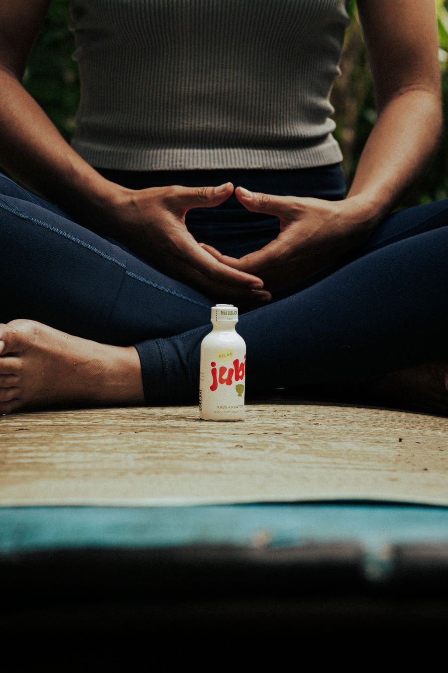 Person meditating with Jubi shot bottle in front.