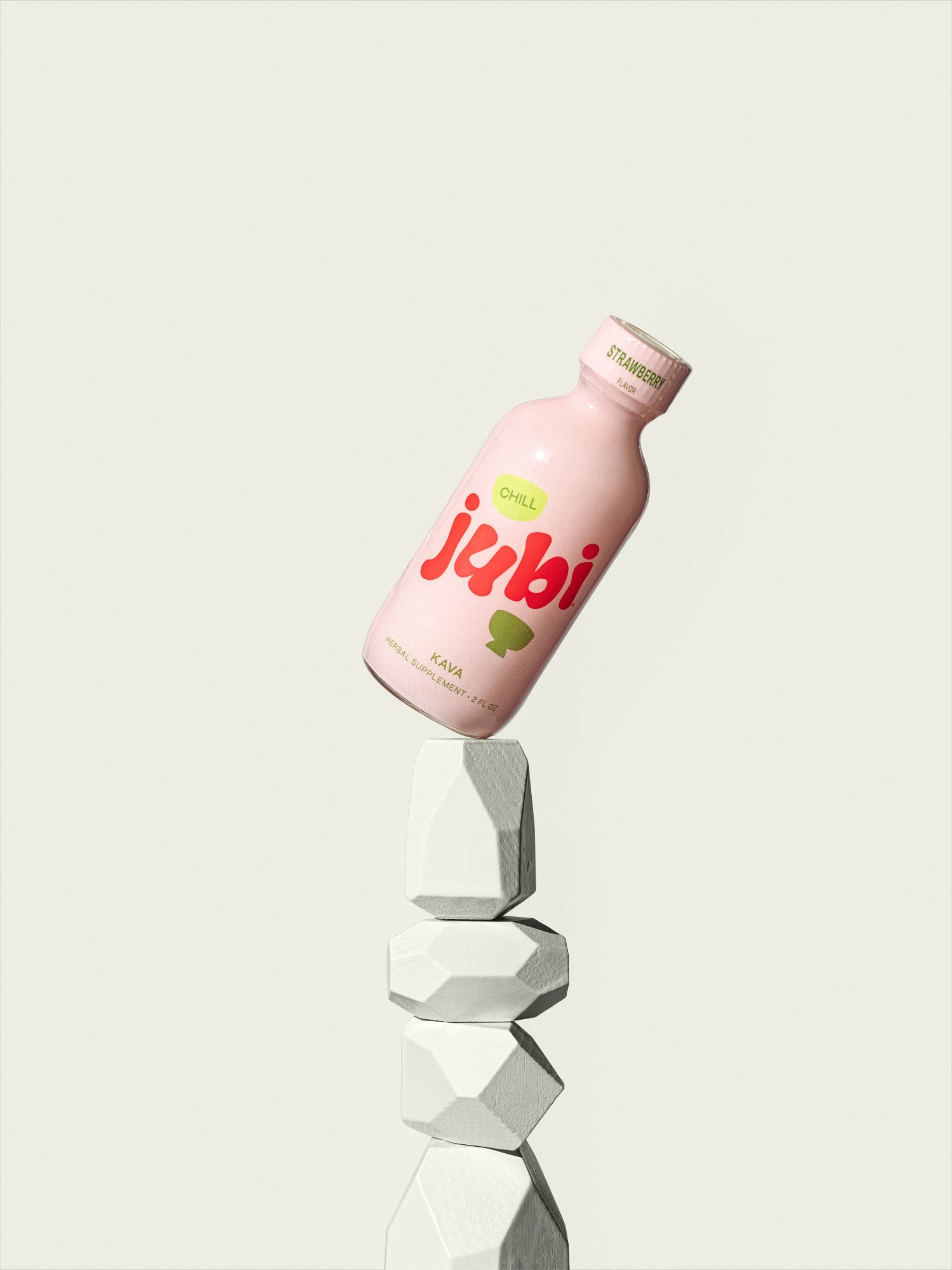 Jubi Strawberry kava shot balanced on stacked stones.