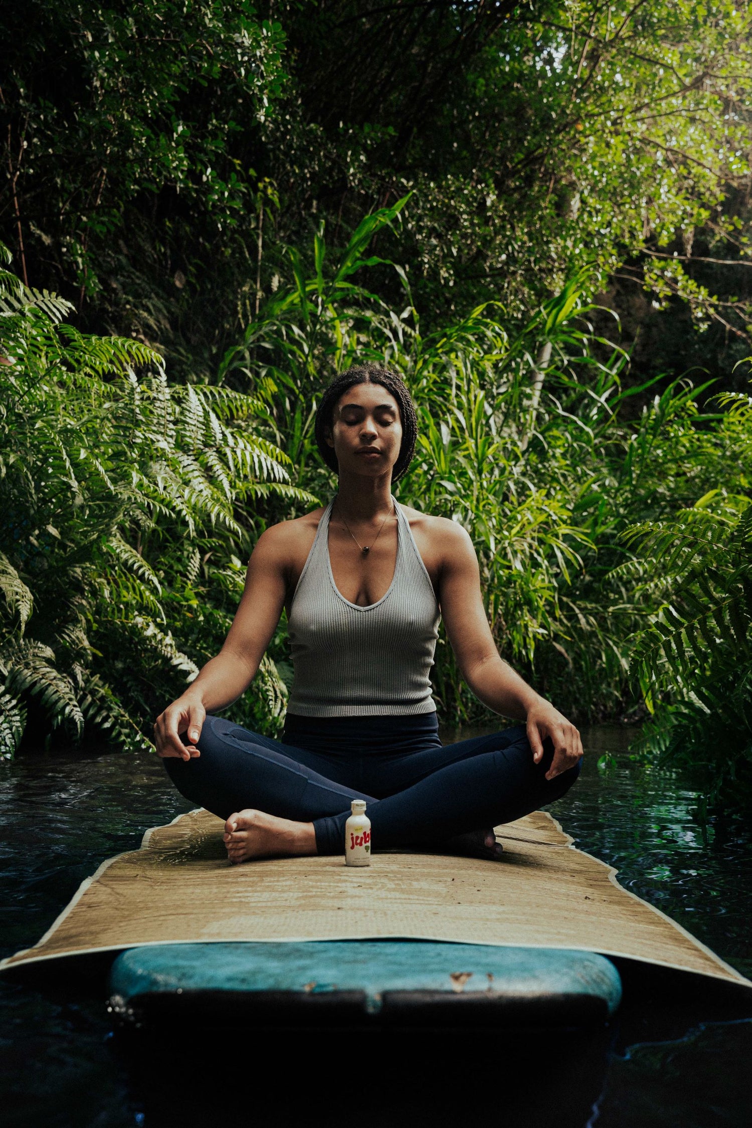 Woman meditating in nature with Jubi bottle.